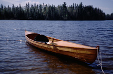 Lutra Voyager wooden canoe afloat on a lake